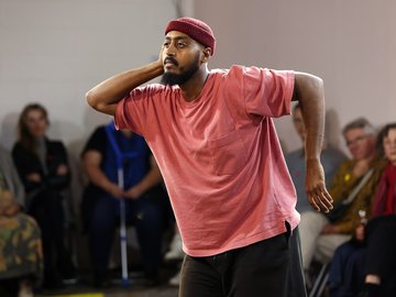 A dancing man, wearing a maroon beanie and red t-shirt.