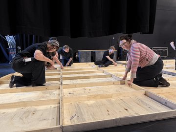 Theatre crew building a wooden set-piece/wall on a stage