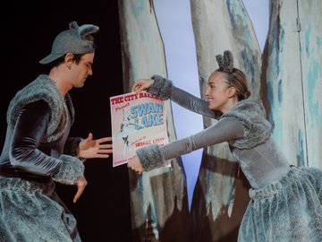 A young man and woman both dressed as a kangaroos, holding a poster for a 'Swan Lake' ballet concert.