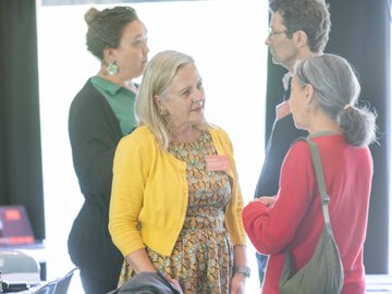 Group of four people in conference wearing name tags and chatting.