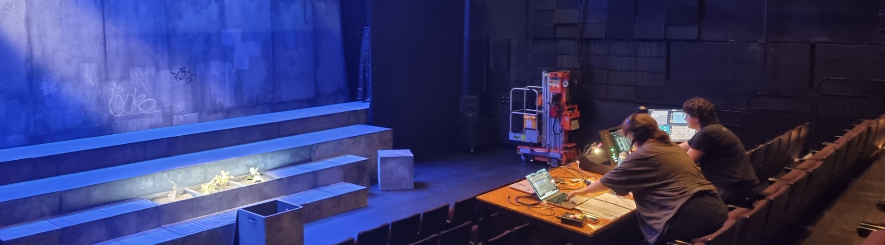 Stage lighting equipment and crew working at control boards in a theatre.
