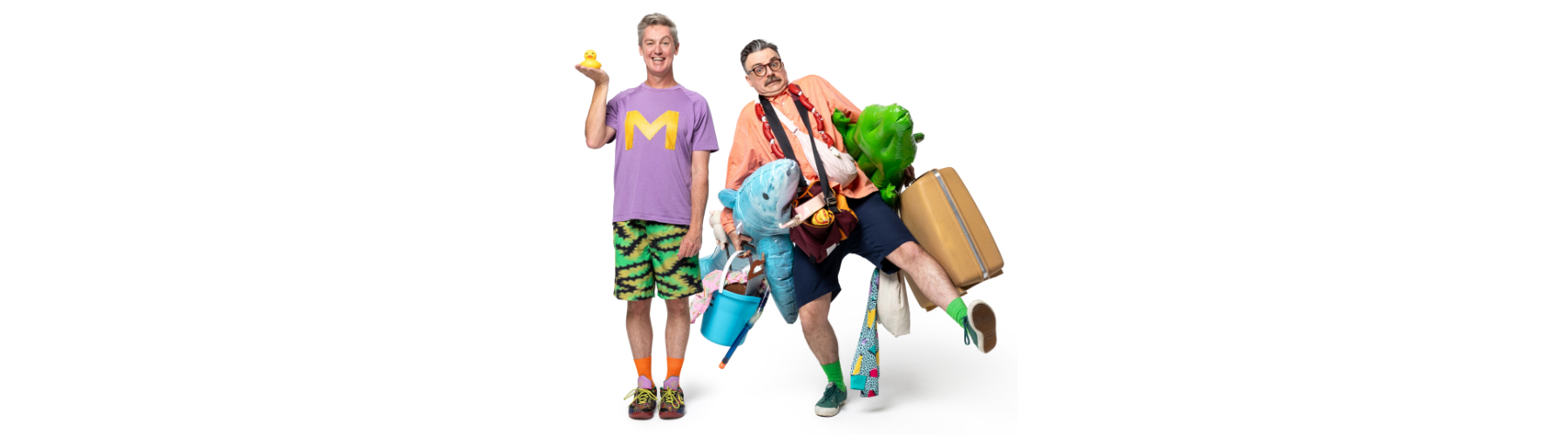 2 men wearing colourful clothes with comedic looks on their faces. One holds a yellow rubber duck and the other is holding a suitcase and lots of toys under his arms.