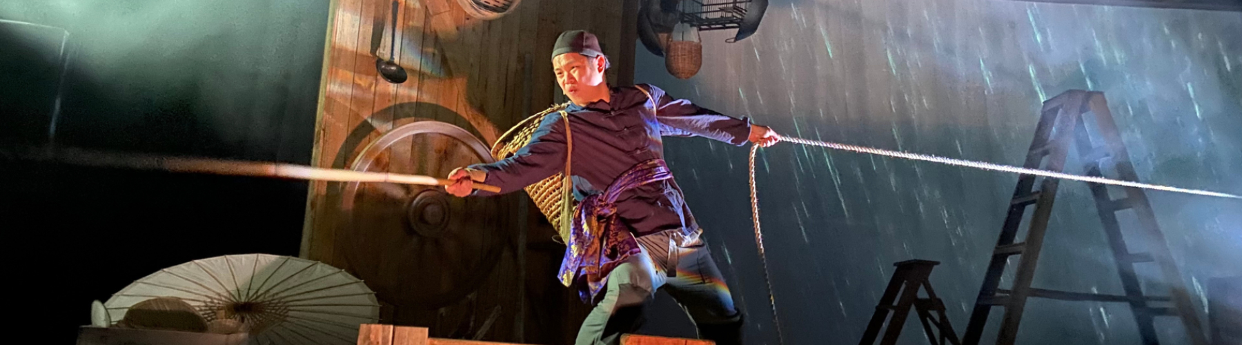 A young Chinese man on a boat in the middle of a storm (on stage)